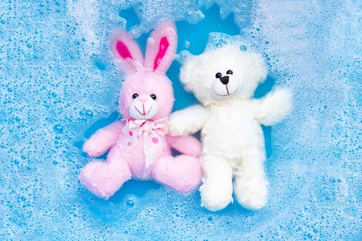 Soak rabbit doll with  toy teddy bear in laundry detergent water dissolution before washing.  Laundry concept, Top view