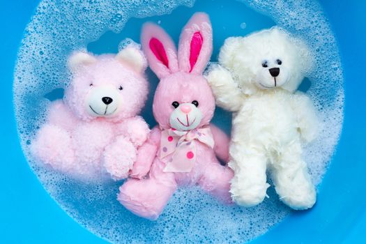 Soak rabbit doll with  toy bears in laundry detergent water dissolution before washing.  Laundry concept, Top view