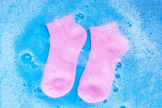 Pink  socks soaking in powder detergent water dissolution. Laundry concept. Top view