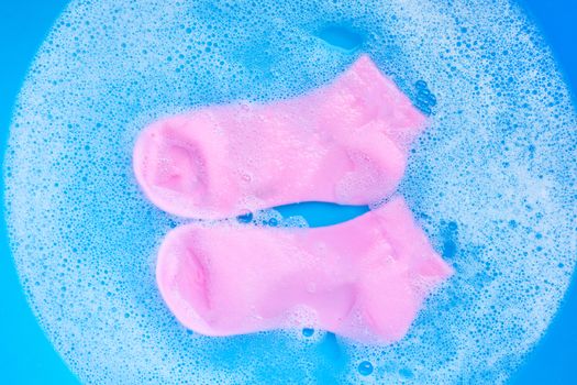 Pink  socks soaking in powder detergent water dissolution. Laundry concept. Top view