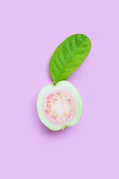 Top view of fresh ripe guava with leaf on pink background.