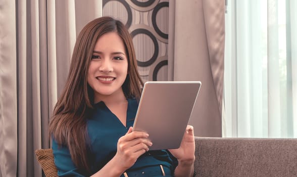Attractive woman is using tablet on sofa