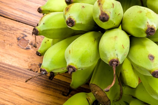 Bunch of unripe banana on wooden background.