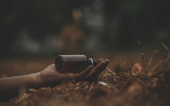 Concept of Farmer Suicide, closeup of hands with poison bottle at farm or agriculture land