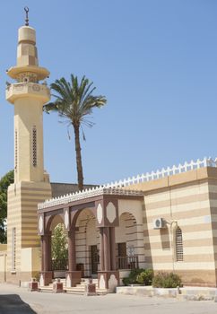 Old striped egyptian mosque building with minaret at El Quseir town