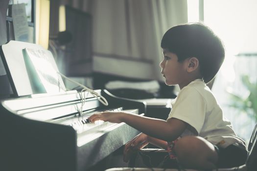 Little Boy is playing with piano and Music Tablet at home
