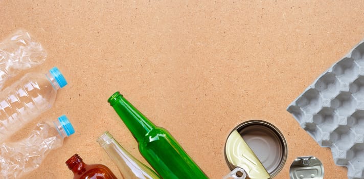 Recyclable garbage, plastic bottle, glass bottle, can and egg paper tray on brown plywood background. Copy space