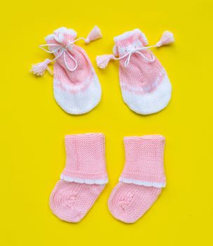 Baby gloves and socks on yellow background. Top view