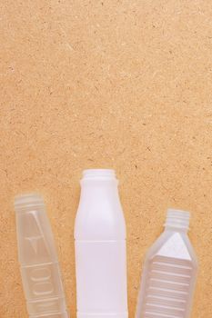 Plastic bottles on plywood background. Copy space