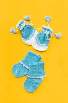 Baby gloves and socks on yellow background. Top view