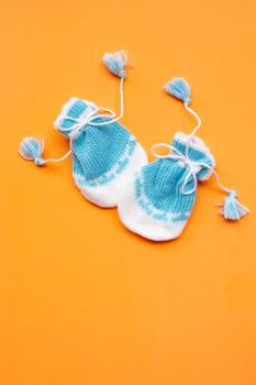 Baby gloves on orange background. Top view