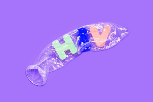 Condom with "HIV" wooden alphabet on purple background.