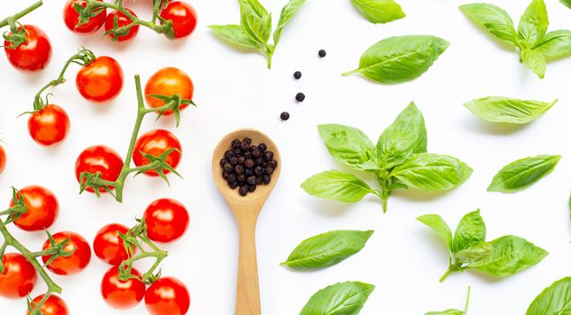 Fresh cherry tomatoes with  black pepper  and  basil leaves on white background. 
