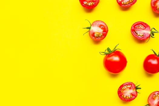 Fresh cherry tomatoes, whole and half cut isolated on yellow background. Copy space