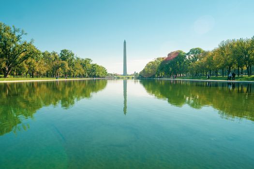 Washington DC USA - October 26 2014; George Washington Monument at end and reflected into the calm long Reflecting Pool line on both sides by trees and parkland on National Mall.