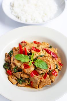 Stir-fried hot and spicy pork with holy basil on white background.