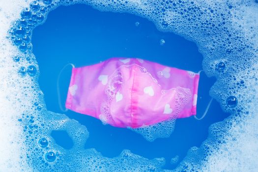 Pink cloth masks soak in powder detergent water dissolution before washing. Hygiene coronavirus (Covid-19) protection concept