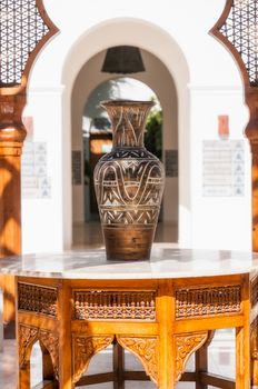 A big egyptian vase on a wood and marble arabian table