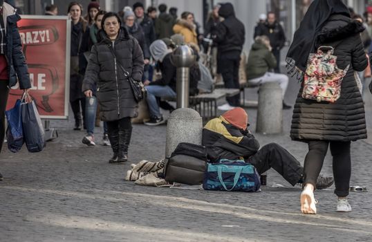 Brunswick, Lower Saxony, Germany, December 7th 2017: Freezing and tired poor beggar in the pedestrian zone in front of the Christmas market of Brunswick.