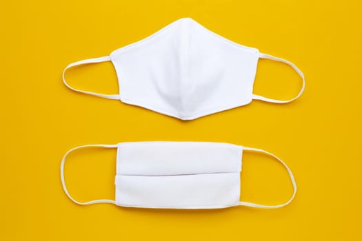  Handmade white cloth masks on cream yellow background.  Top view