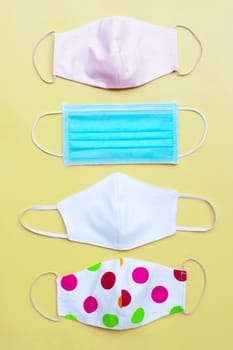 Protective medical mask with cloth masks on yellow background. Top view