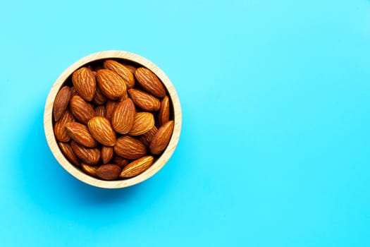 Almonds in wooden bowl on blue background. Copy space