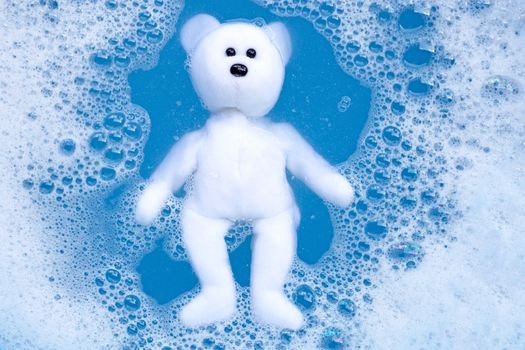 Soaking bear toy in laundry detergent water dissolution before washing. Laundry concept, Top view