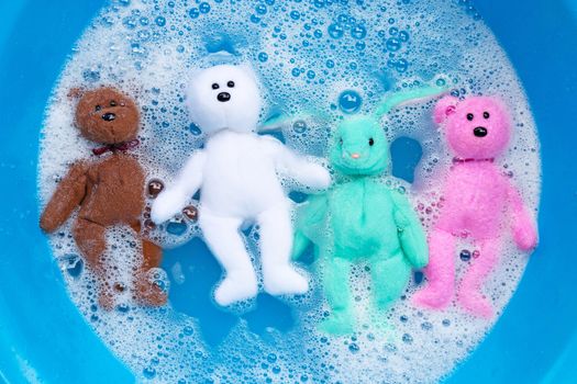 Soak rabbit dolls with  bear toys in laundry detergent water dissolution before washing.  Laundry concept, Top view