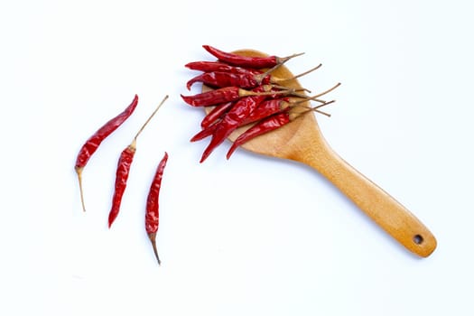 Dry red hot chili peppers on wooden spoon on white background. 