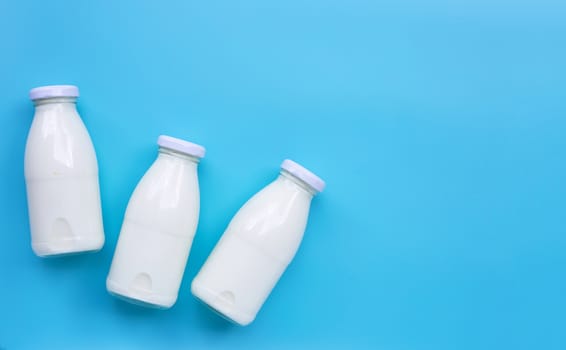 Milk bottles on blue background. Copy space