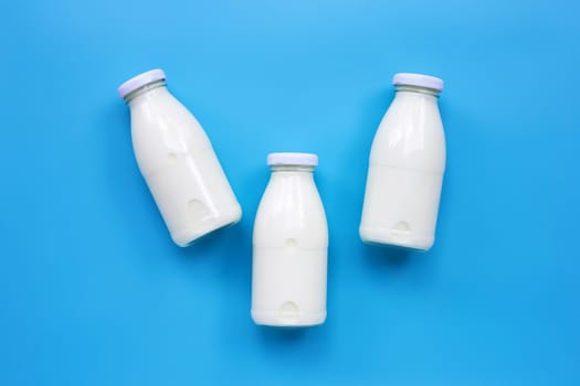 Milk bottles on blue background. Copy space