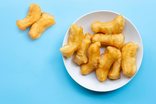 Deep-fried dough stick, chinese bread stick on white dish. Blue background with copy space
