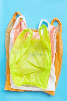 Colorful plastic bags on blue background. Environment pollution concept. Top view