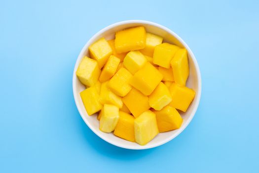 Tropical fruit, Mango cube slices in white bowl on blue background. Top view