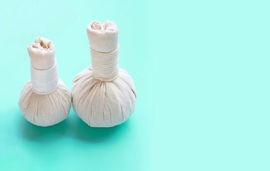 Herbal compress balls for Thai massage and spa treatment on green background.  Copy space