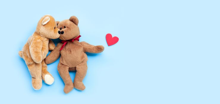 Bear toy couple with heart on blue background. Copy space