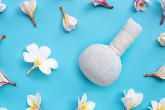 Plumeria or frangipani flower with herbal compress ball for Thai massage and spa treatment  on blue background. Top view