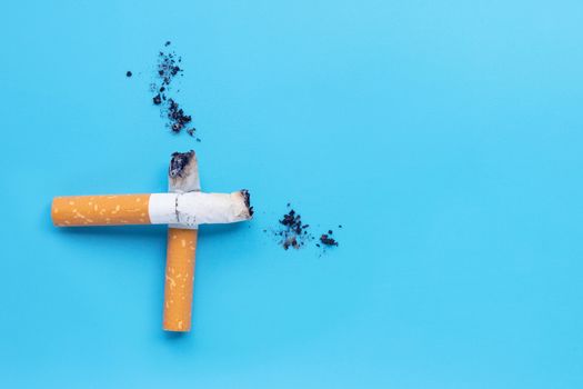 Cigarette butts and ashes on blue background. Copy space