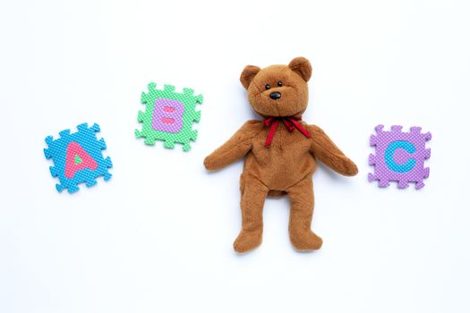 Bear toy with english alphabet puzzle on blue background. Education concept, Copy space
