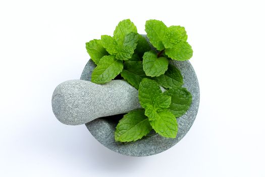 Mint leaves in stone mortar and pestle on white background. Top view
