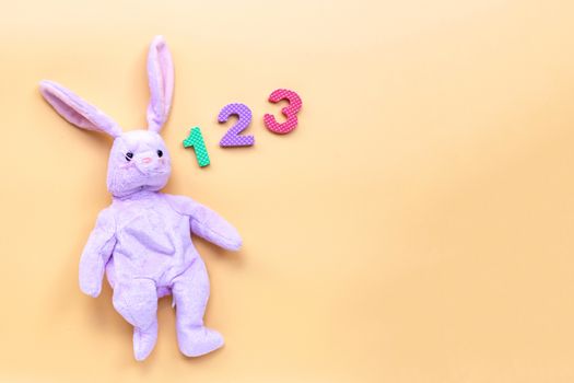 Rabbit toy with  numerals on yellow background. Education concept, Copy space