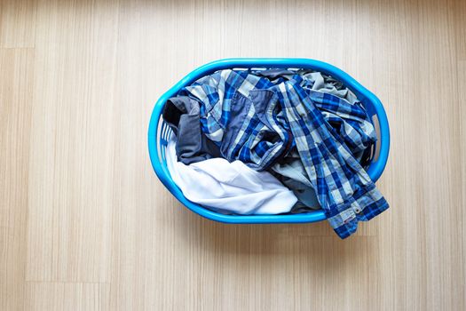 Clothes in blue plastic laundry basket. Top view
