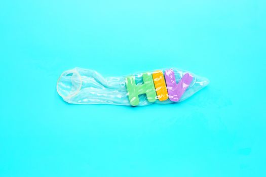 Condom with  "HIV" colorful alphabet on blue background. Save sex concept, Topv view