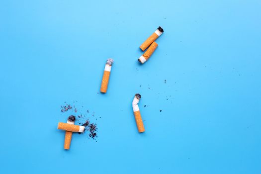 Cigarette butts on blue background. Copy space