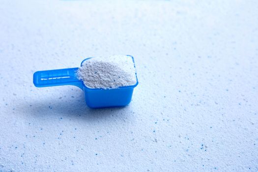 Blue measuring scoop with laundry powder. Copy space