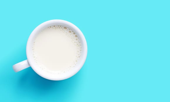 Cup of milk on blue background. Copy space