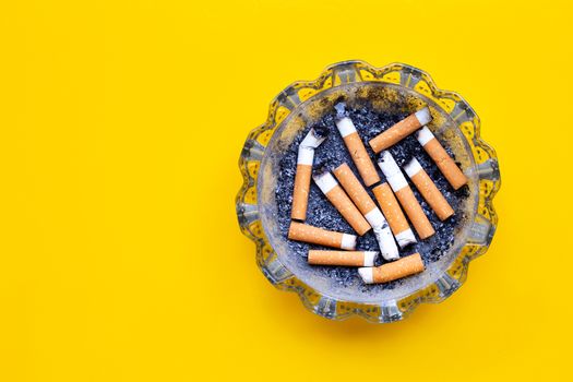Smoked cigarettes on yellow background. Copy space