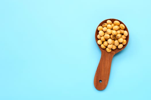 Soy Beans with wooden spoon on blue background.