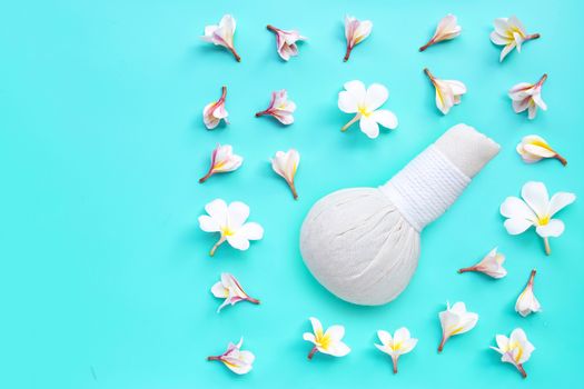 Plumeria or frangipani flower with herbal compress ball for Thai massage and spa treatment on blue background. Top view