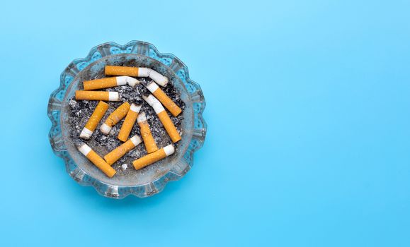 Smoked cigarettes on blue background. Copy space